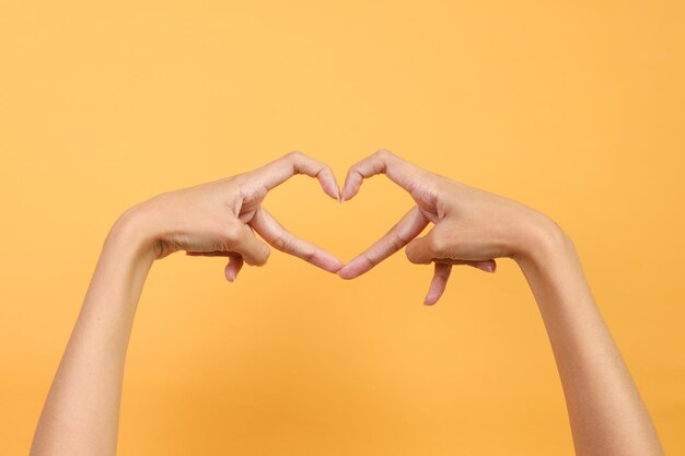 Dedos formando forma de coração ou amor isolados em fundo amarelo