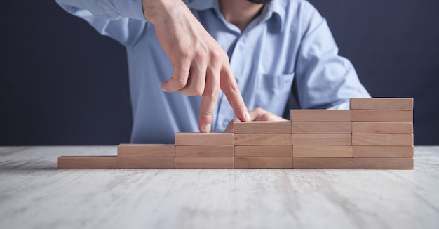 Dedos masculinos subiendo escaleras sobre bloques de madera.