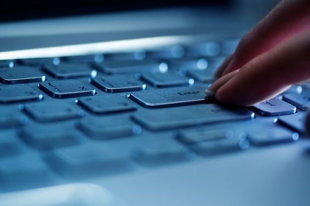 Dedos de mujer en el teclado del portátil en la oficina