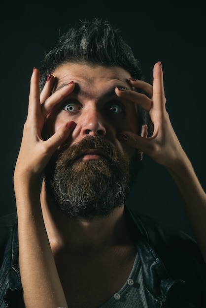 Los dedos de las mujeres con manicura abren los ojos bien abiertos apuesto hombre sorprendido sorprendido asombrado barbudo en