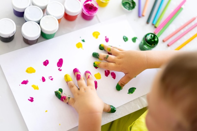 Los dedos de los niños dibujan una imagen brillante con colores, las palmas de las manos del niño están cerradas