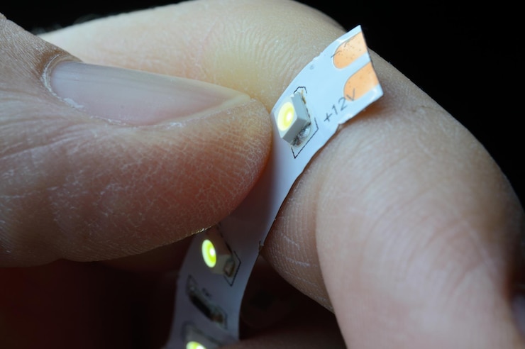 Foto los dedos de una persona sostienen una tira de led brillante de 12 voltios. de cerca