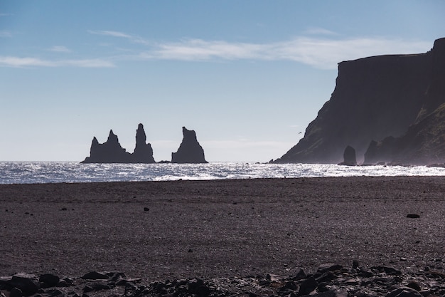 Los dedos de Rock Troll en el océano cerca de la playa con arena negra en el sur de Islandia