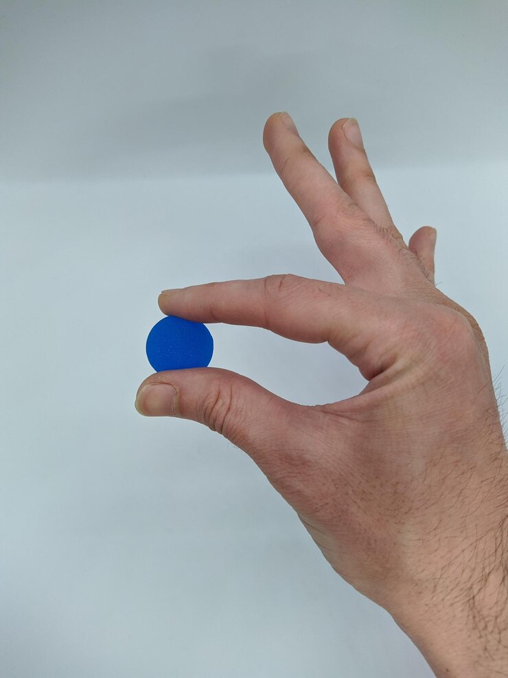 Foto los dedos sosteniendo una pequeña pelota azul sobre un fondo blanco