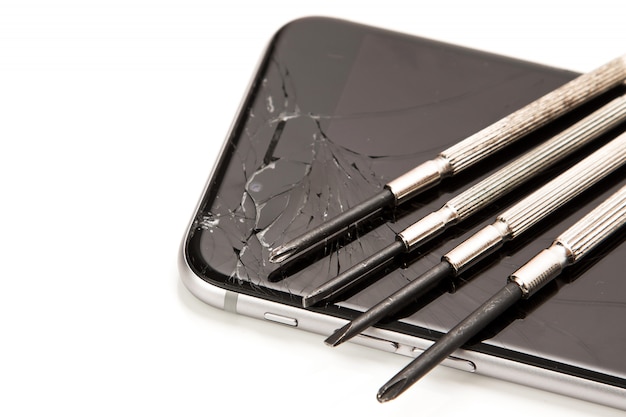 Defektes Smartphone und kleine Schraubendreher zur Reparatur
