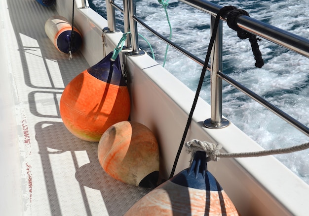 Defensas laranja no convés do navio indo para o mar.