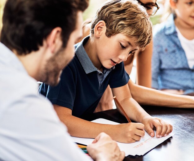 Definitivamente está sacando una A por esfuerzo Foto de un niño pequeño haciendo su tarea con la ayuda de su padre