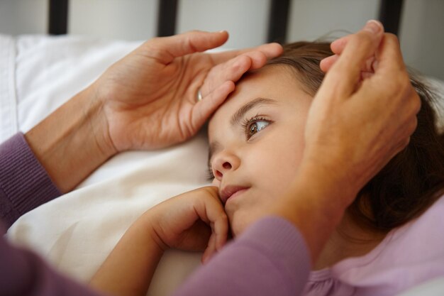 Definitivamente tengo su atención ahora Foto de una madre cariñosa tocando la frente de su niña enferma