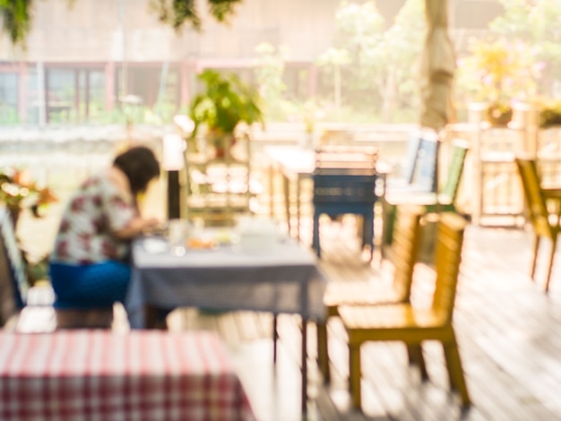 Defocused von der Frau, die Lebensmittel unter Sonnenlicht im Restaurant isst