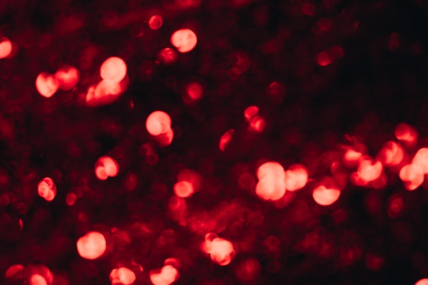 Defokussierte Funken Bokeh-Lichtüberlagerung Blur-Glanz-Strahlung Neonrote Farbe glüht rundes Fleckenmuster auf dunkelschwarzem abstraktem Hintergrund