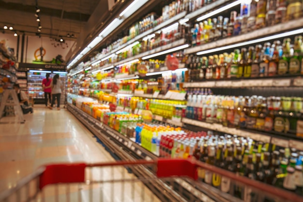 Defokussierte Unschärfe von männlichen und weiblichen Einkaufswagen, die beim Einkaufen von alkoholischen Getränkeprodukten im Supermarkt einkaufen?