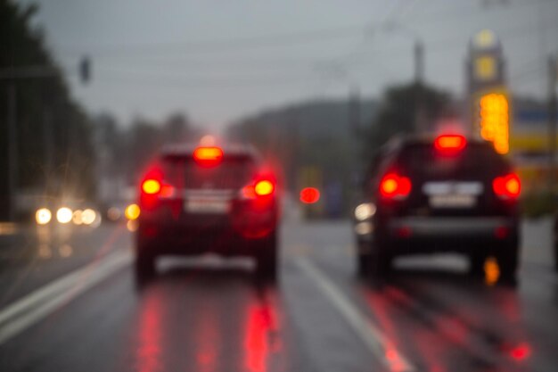 Defokussiertes Bild des Straßenautoverkehrs am Abend nach Regenblick von der Straße