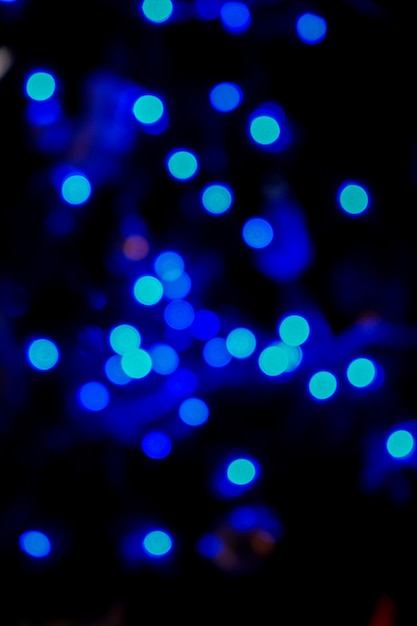 Defokussiertes blaues Bokeh-Licht des Weihnachtsbaums in der Nacht. Blauer Bokeh-Hintergrund. Festliche bunte Kulisse