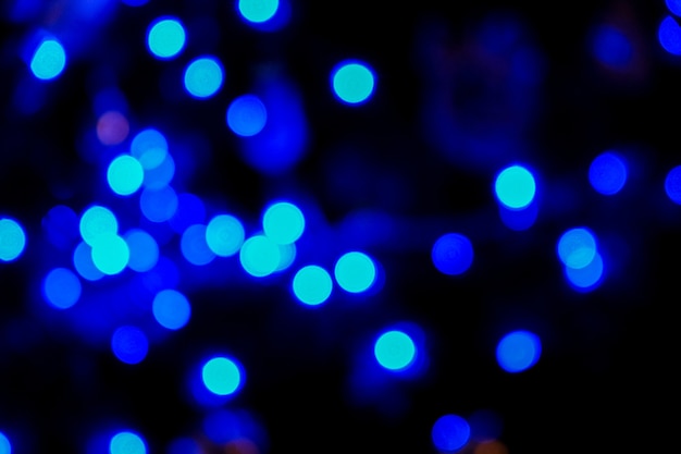 Defokussiertes blaues Bokeh-Licht des Weihnachtsbaums in der Nacht. Blauer Bokeh-Hintergrund. Festliche bunte Kulisse