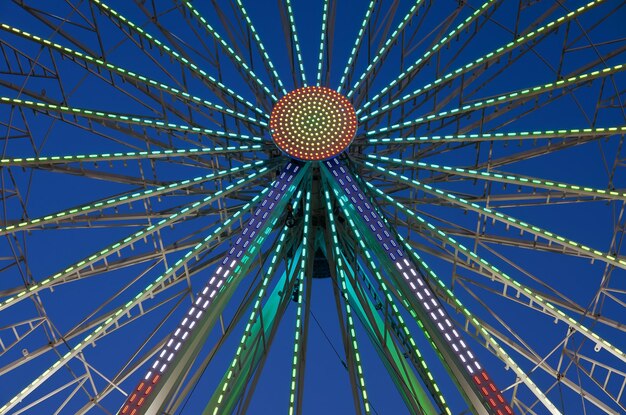 Defokussiertes und unscharfes Bild des Vergnügungsparks bei Nacht. Riesenrad und Achterbahn in Bokeh-Lichtern