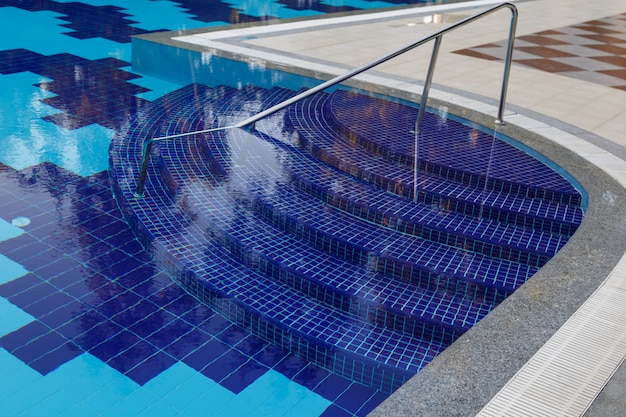 Foto degraus semicirculares de cor azul na grande piscina com água límpida