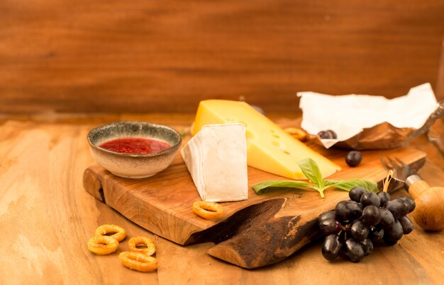 Degustação de queijo prato com ervas e frutas na mesa de madeira