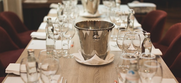 Foto degustação de vinhos: mesa servida com listas de degustação, copos, garrafas com água e escarradeira.