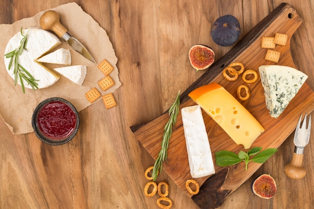 Degustación de plato de queso con hierbas y frutas en la mesa de madera