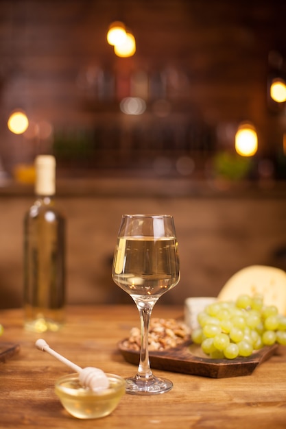 Degustación de vinos en un pub vintage con uvas frescas en una mesa de madera. Cuenco de miel sabrosa.