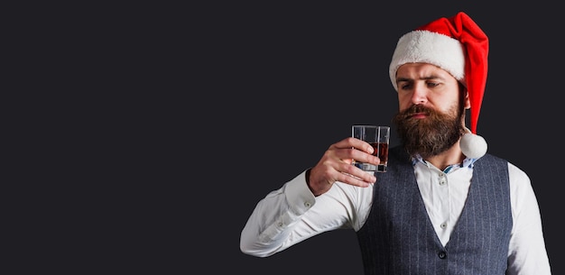 Degustación de whisky bebe whisky escocés o sommelier de coñac hombre barbudo con sombrero de navidad con vaso de