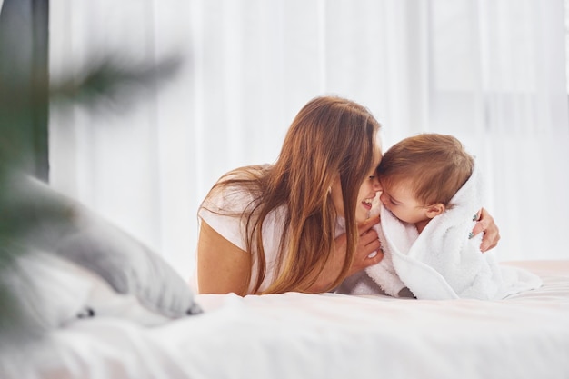 Deitada na cama Mãe com sua filha está dentro de casa juntos