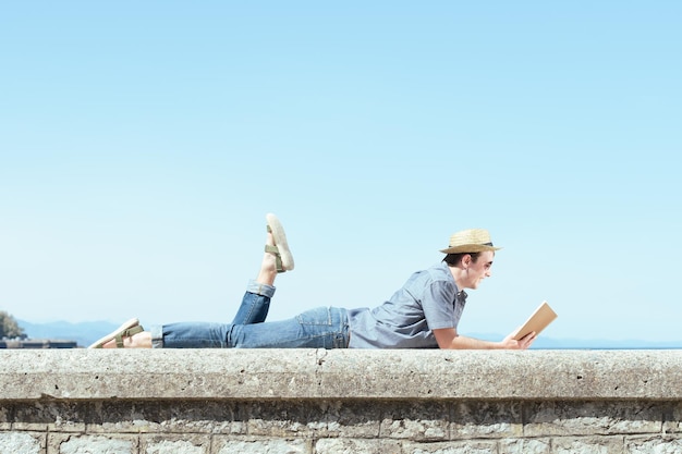 Deitado homem feliz lendo um livro no verão