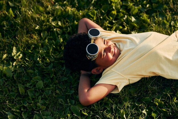 Deitado na grama, criança afro-americana se diverte no campo no dia de verão