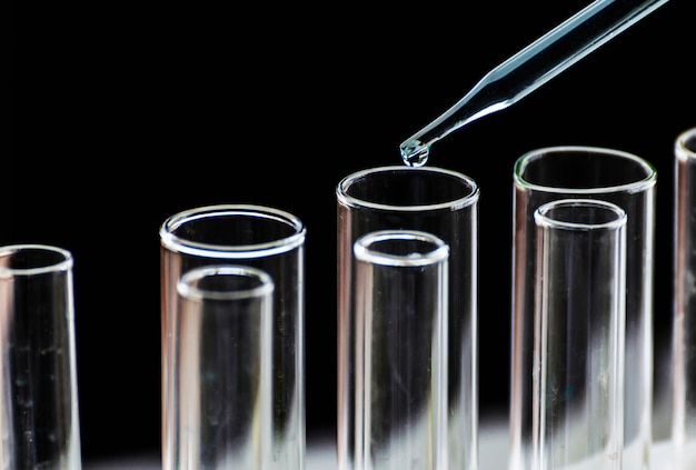 Deixar cair o líquido químico ao tubo de ensaio, conceito da pesquisa da ciência.