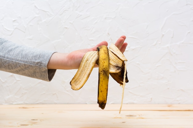 Deja de desperdiciar comida. la mano de los niños sostiene una cáscara podrida de plátano.