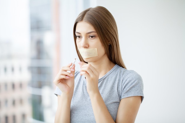 Deja de fumar mujer joven sosteniendo un cigarrillo roto