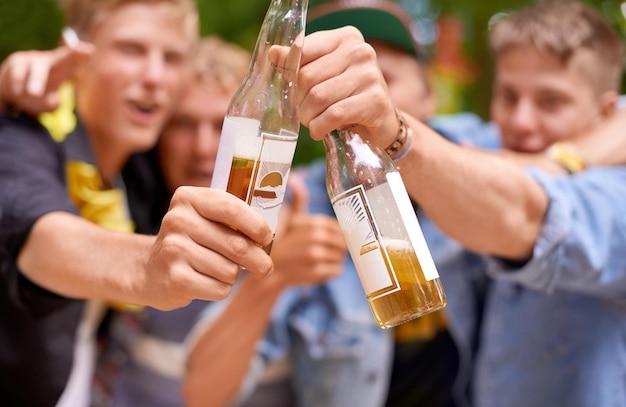 Deja que los buenos tiempos fluyan Toma recortada de un grupo de jóvenes brindando con botellas de cerveza