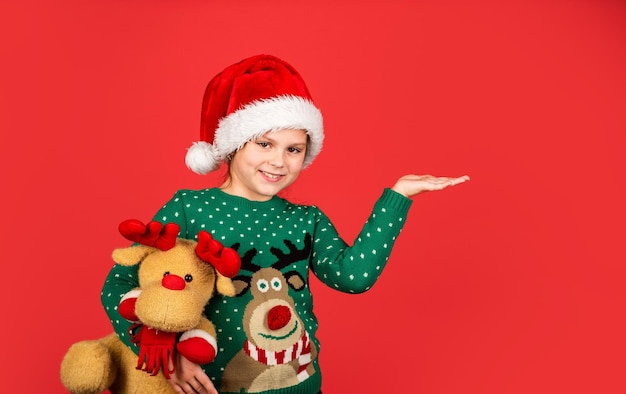 Deja que tu Navidad sea brillante. felicidad infantil. juguete de regalo de retención de duendecillo. preparación de año nuevo. copie el espacio. tiempo de compras navideñas. juguetería y obsequios para niños. niño sonriente con sombrero de santa.