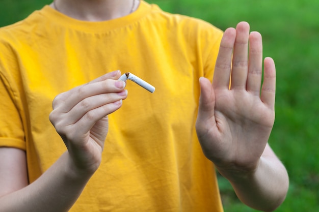 Dejar de fumar concepto de cigarrillos. Retrato de la muchacha sonriente hermosa que sostiene el cigarrillo roto en manos. Feliz mujer dejar de fumar cigarrillos. Dejar el mal hábito, el concepto de atención médica. No Fumar.