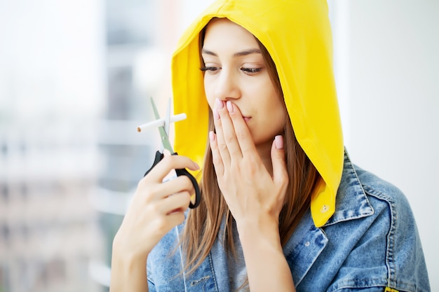 Deje de fumar, una mujer joven rompe un cigarrillo instando a dejar de fumar