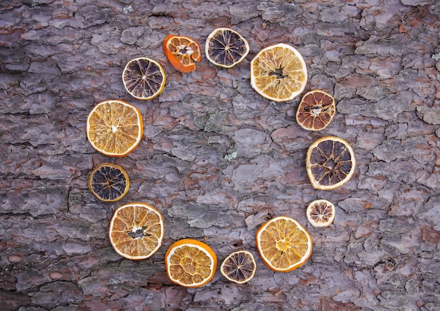 Dekor aus getrockneten Orangenscheiben auf rauer Struktur der Baumrinde.