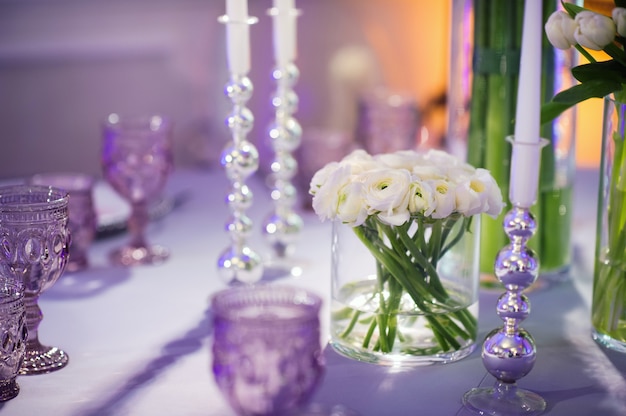 Dekoration des festlichen Abendessens am Abend mit Blumen auf dem Hochzeitstisch im Inneren des Restaurants. Hochzeitsdekoration.