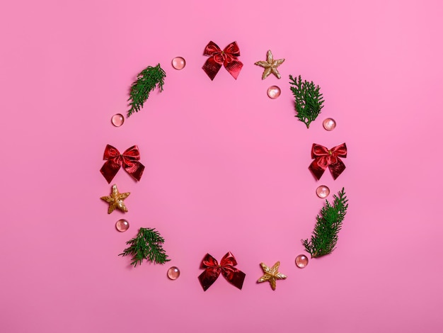 Dekorationen für Merry Christmas Card rote Bögen Perlen Strohsterne und grüne Zweige auf rosa Hintergrund