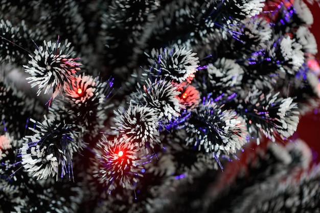 Foto dekorative baumzweige, die mit girlandenbeleuchtung geschmückt sind bokeh im hintergrund von zweig-led-girlanden xmas-neujahrskarte schnee bedeckt künstlicher weihnachtsbaum weihnachtenbaum rote led-beleuchtung