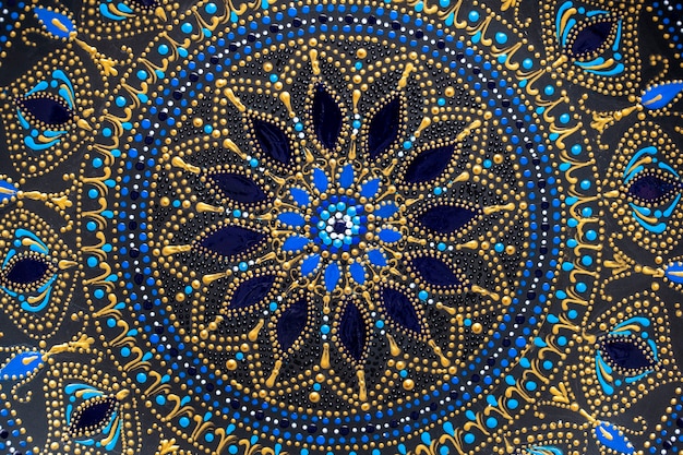 Dekorative Keramikplatte mit schwarzen, blauen und goldenen Farben, bemalte Platte im Hintergrund, Nahaufnahme, Draufsicht. Detail Porzellanteller mit Acrylfarben bemalt, Handarbeit, Punktmalerei