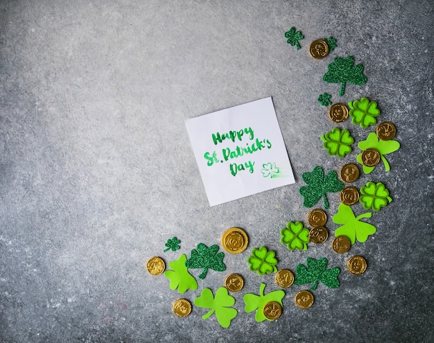 Foto dekorative kleeblätter, grüne geschenkbox, münzen auf steinhintergrund, flache lage. feier zum st. patrick's day. karte happy st. patrick's day