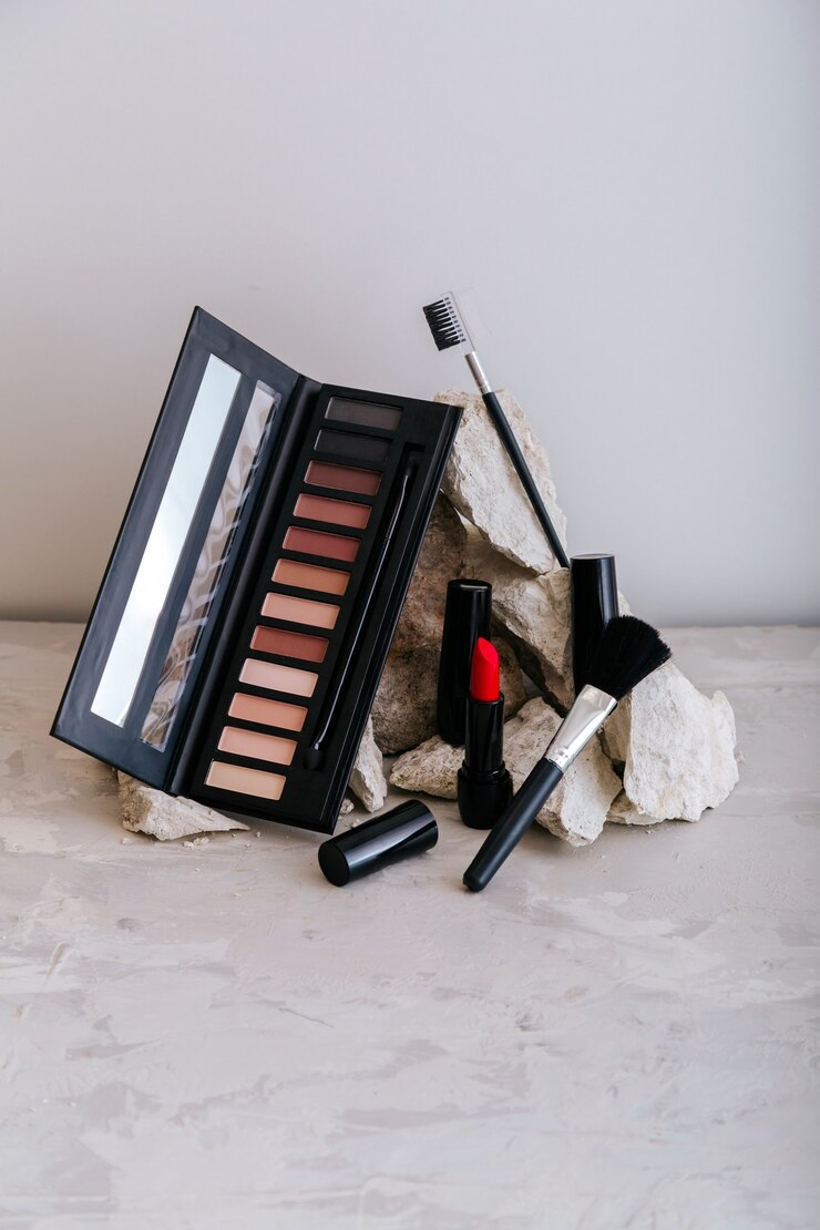 Dekorative Kosmetik für Make-up auf Steinsockel. Rote scharlachrote Lippenstift-Lidschatten-Make-up-Pinsel auf grauem Betonhintergrund. Minimale Ästhetik. Beauty Fashion Make-up-Produkte.