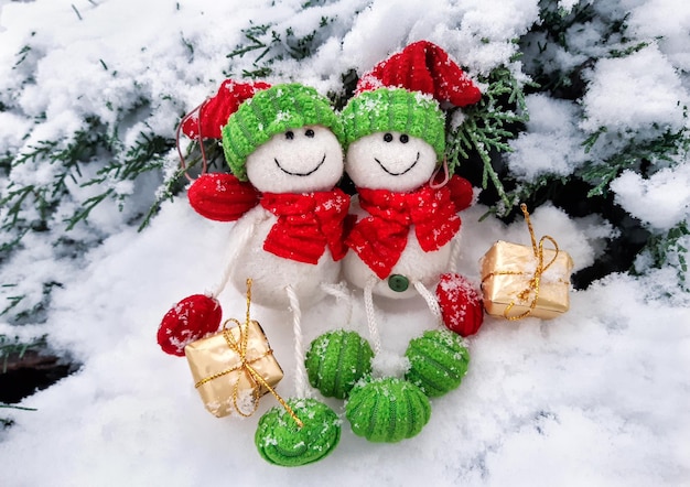 Dekorative Weihnachts- und Frohes neues Jahr-Komposition von lustigen zwei Schneemännern in Hüten und Schals mit Geschenken, die im Schnee sitzen. Feier Weihnachtslandschaft.