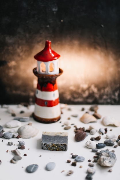 dekorativer Leuchtturm mit Muscheln und Kieselsteinen