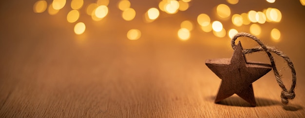 Dekorativer Weihnachtsstern aus Holz auf dem Hintergrund von Bokeh-Lichtern