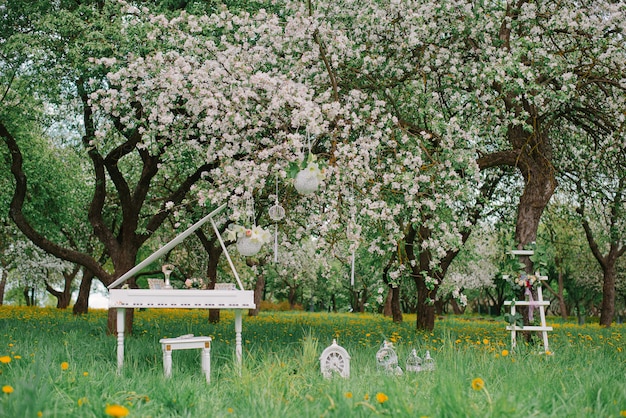 Dekorativer weißer Stehleiter und weißer Flügel in einem blühenden Garten im Frühjahr. Romantisches Dekor