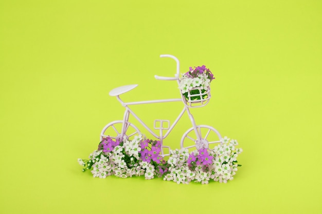 Dekoratives Fahrrad mit Blumen auf gelbem Hintergrund. Frühling minimalistisches Konzept