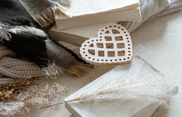 Dekoratives Herz, Strickwaren und Bücher. Das Konzept des Valentinstags und des Wohnkomforts.