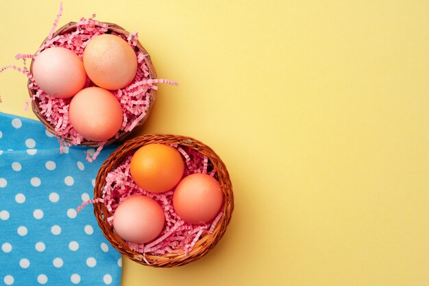 Dekoratives Nest mit bunten Ostereiern auf gelbem Hintergrund