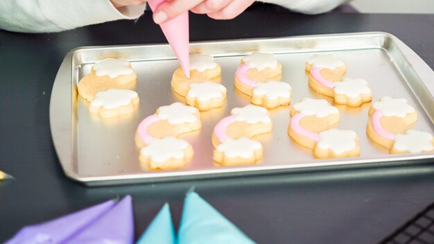 Dekorieren von Einhorn-Zuckerkeksen mit mehrfarbiger königlicher Glasur.